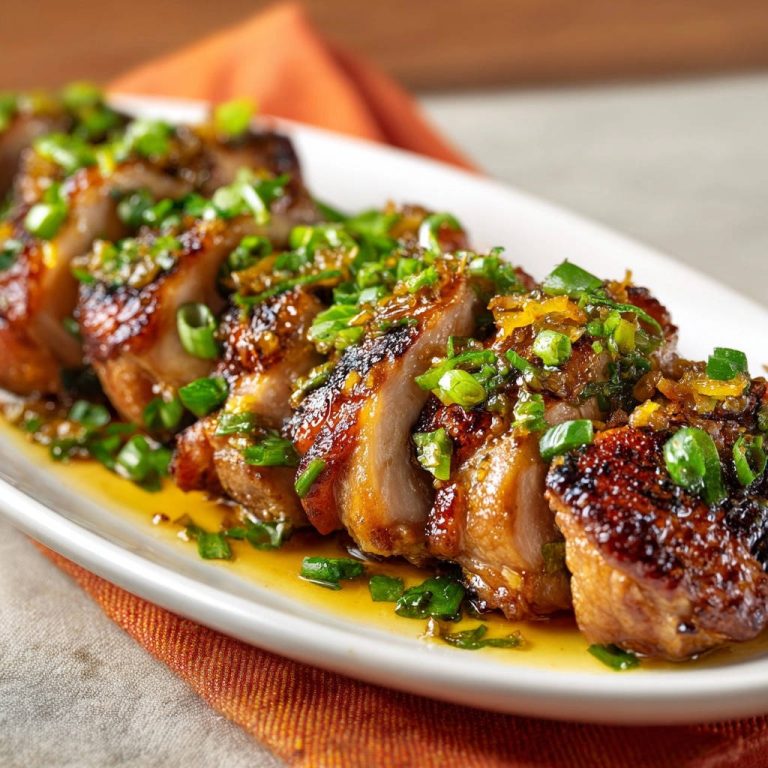 Pan-seared duck breast, sliced and glistening with a savory glaze and fresh scallion garnish.