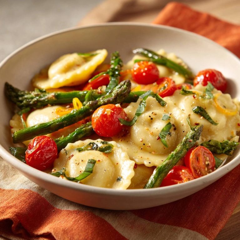 Spring ravioli with roasted veggies served in a bowl, featuring asparagus and cherry tomatoes with fresh basil.