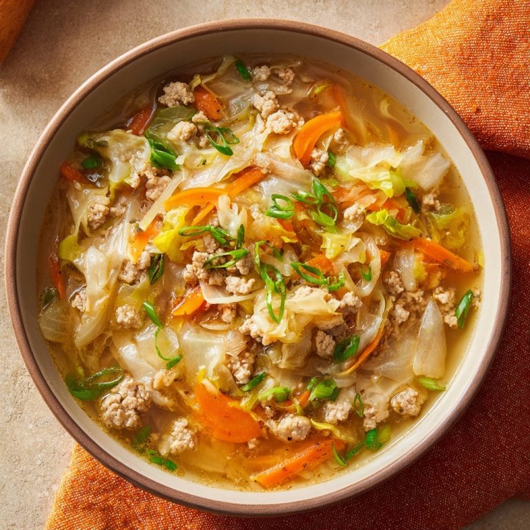 Deconstructed egg roll soup served in a rustic bowl, showcasing tender cabbage, ground pork, and fresh scallion garnish.