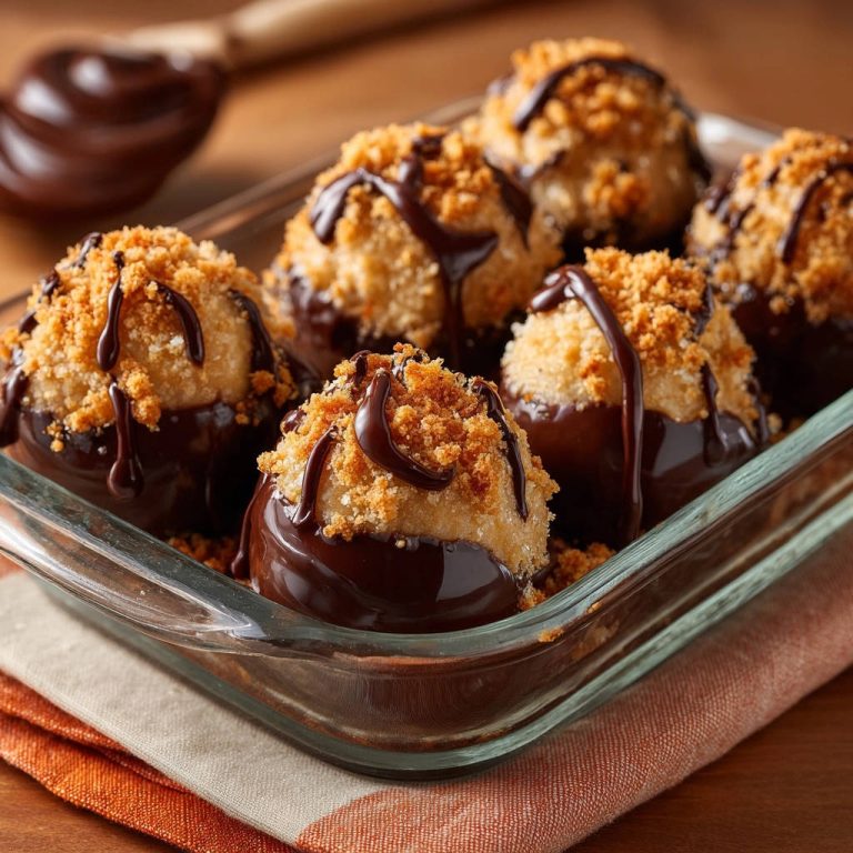 Chocolate-dipped coconut cookie bites in a glass dish, drizzled with chocolate and topped with cookie crumbs.