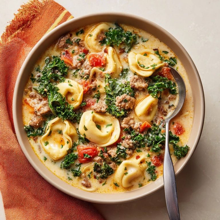 Creamy sausage and tortellini soup in a bowl, showcasing tender pasta and greens from an overhead view.