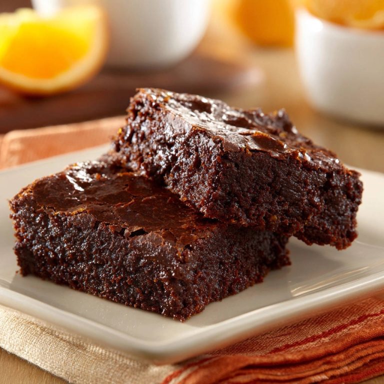 Fudgy chocolate orange brownies stacked on a plate, showcasing their rich texture and moist interior.