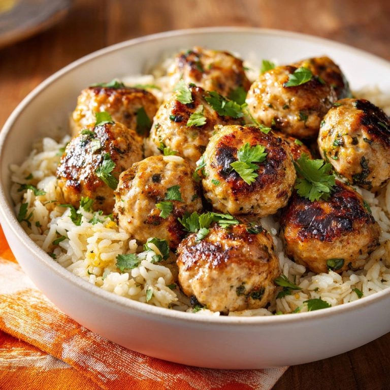 Juicy chicken meatballs with rice, garnished with fresh cilantro, served in a white bowl.