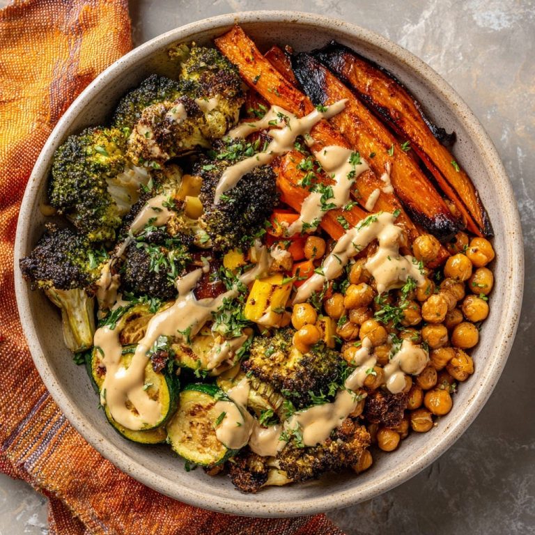 Sheet pan veggie & chickpea power bowl drizzled with tahini sauce, shown from an overhead perspective.