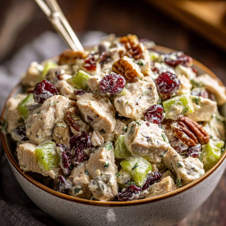 Creamy cranberry pecan chicken salad shown in a bowl with a close-up view of chicken, celery, cranberries, and pecans.