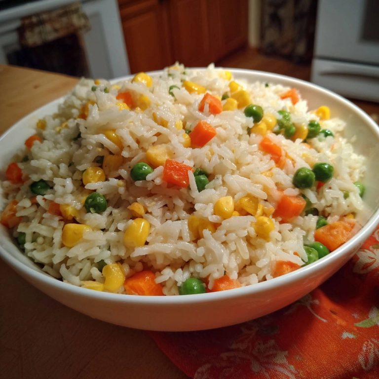 Easy fluffy veggie rice shown in a close-up view inside a white bowl with visible peas, corn, and carrots.