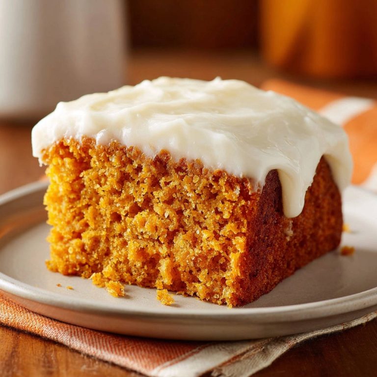 Classic Pumpkin Sheet Cake, a moist slice topped with creamy white frosting, presented on a plate.