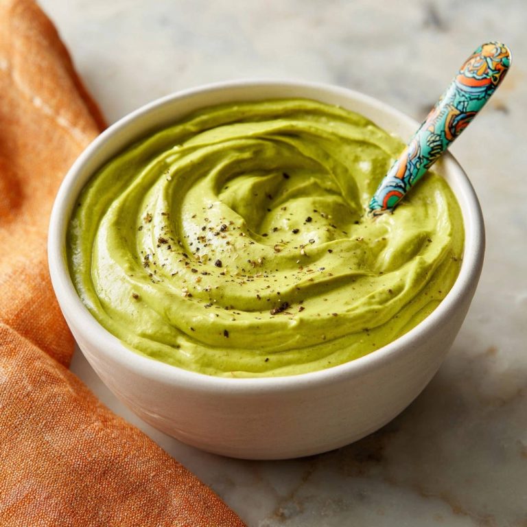 Ultra-creamy avocado dream dip with a beautiful swirl and sprinkled with pepper, served in a white bowl.
