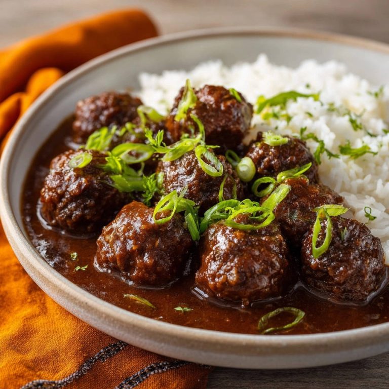 Classic homestyle meatballs and gravy served in a bowl, garnished with fresh green onions.