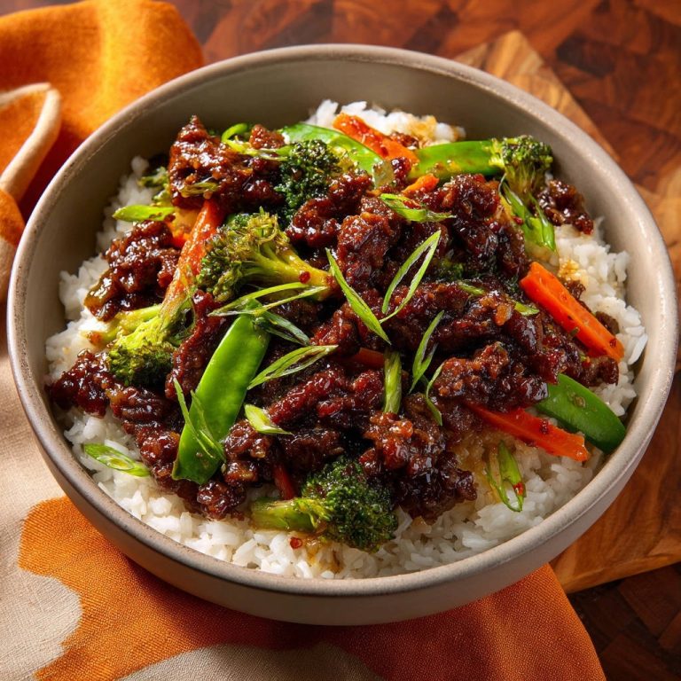 Sticky garlic beef and broccoli bowl close-up serving with tender beef and vibrant vegetables over white rice.