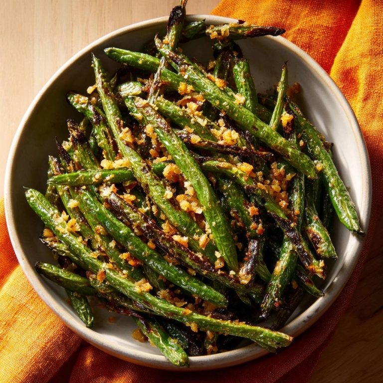 Blistered green beans with crispy garlic served in a light grey bowl, viewed from directly above.