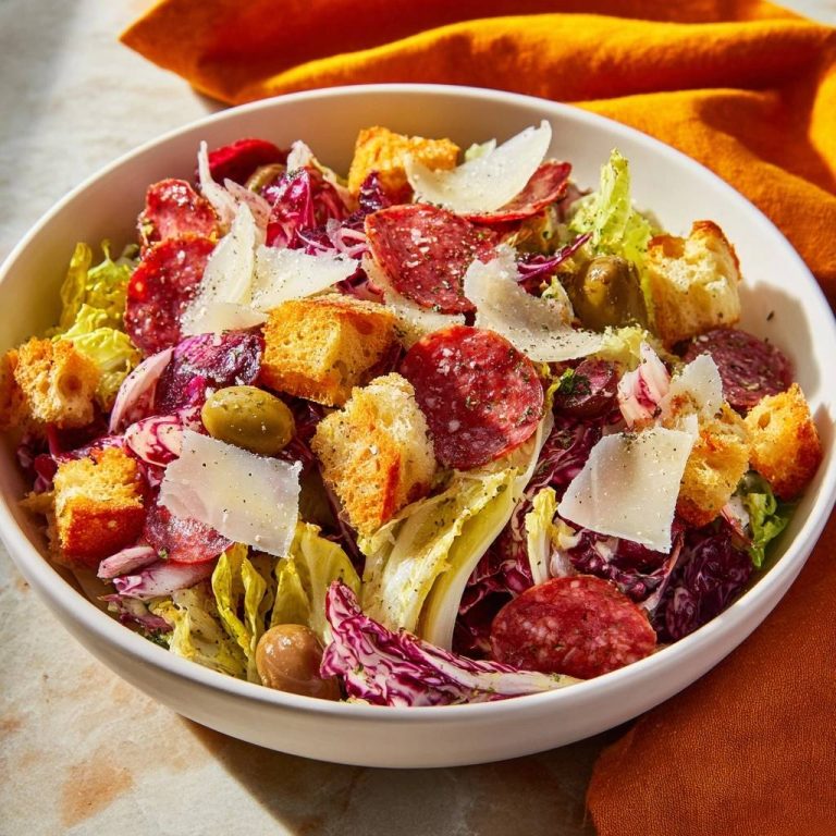 Bold deli salad in a white bowl, featuring salami, croutons, and radicchio with a close-up view.