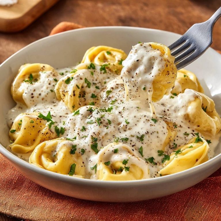 Creamy pepper ravioli with silky sauce, a fork lifts a ravioli showing its creamy filling and peppered sauce.