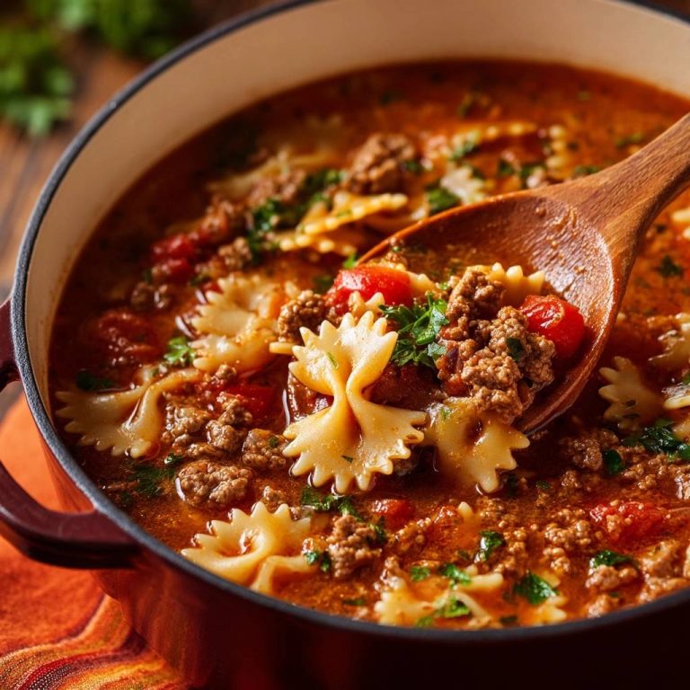 Hearty beef bowtie tomato soup shown in a spoonful detail with pasta, ground beef, and tomatoes.