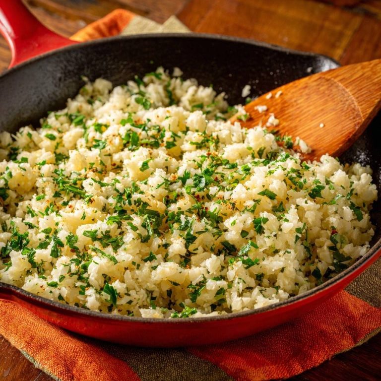 Easy skillet cauliflower rice with fresh parsley garnish in a red cast iron pan
