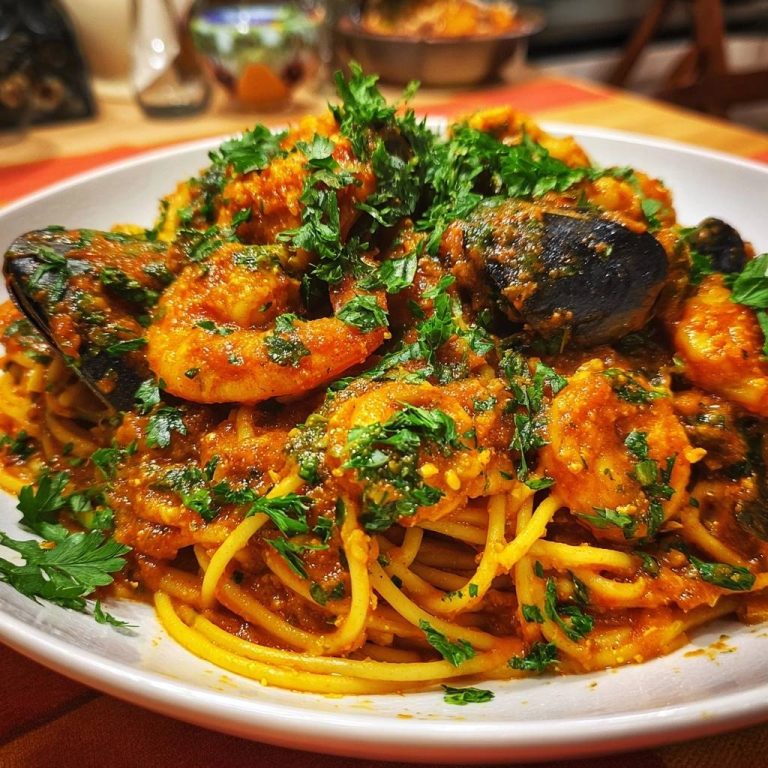 Spicy shrimp mussel pasta featuring a close-up of tender seafood and a fresh parsley garnish.