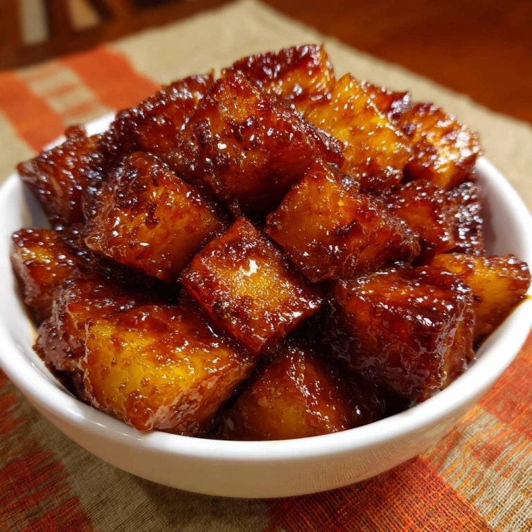 Sticky soy glazed chicken bites shown in a white bowl, featuring a close-up view of the glistening, bite-sized pieces.