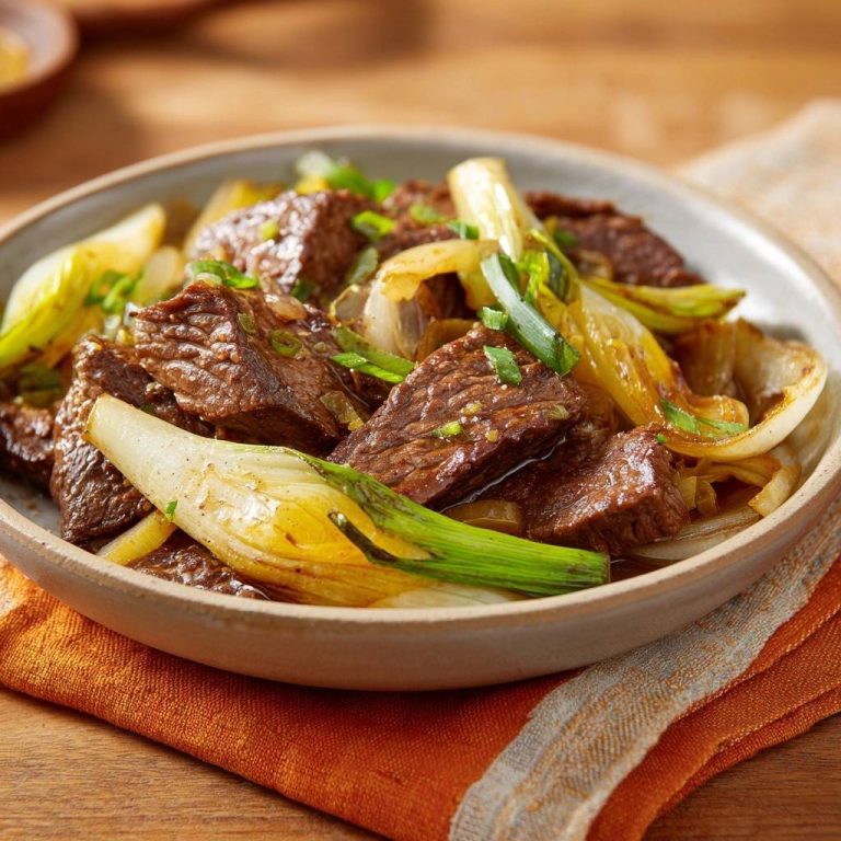 Beef, bok choy, and onion stir-fry served in a bowl, a close-up showing tender beef and wilted bok choy.