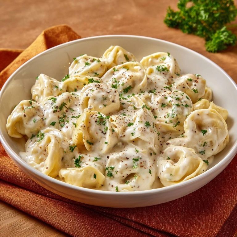 Silky cheese ravioli with flawless cream sauce served in a white bowl, garnished with fresh parsley and black pepper.