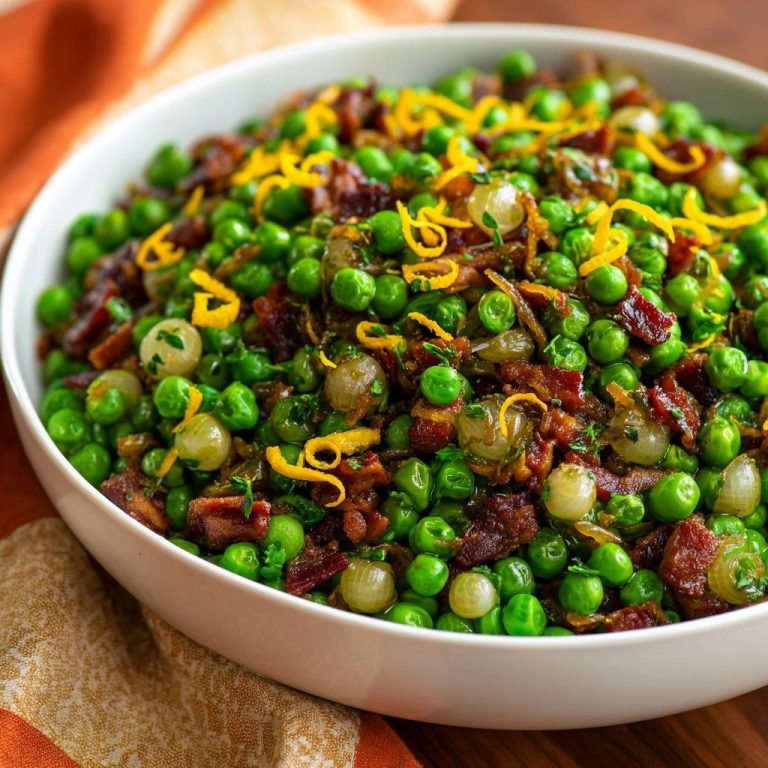 Zesty bacon peas with pearl onions served in a white bowl, garnished with lemon zest and fresh herbs.