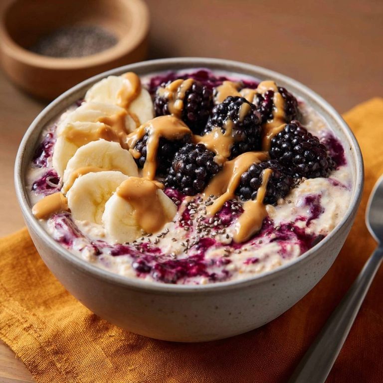 Creamy blackberry peanut butter oatmeal drizzled with peanut butter and topped with fresh blackberries and banana slices.