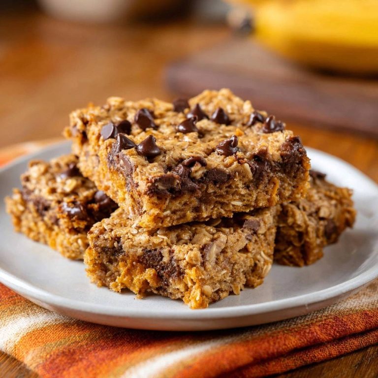 Chocolate chip banana oat bars stacked up close on a white plate, showcasing their texture and chocolate chips.