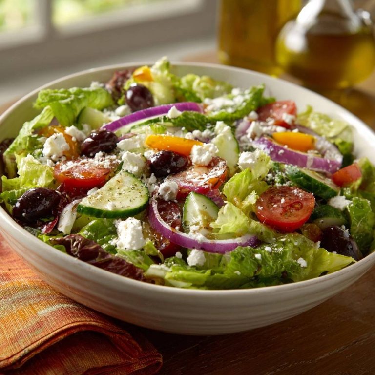 Classic Greek salad with feta cheese, cucumber slices, Kalamata olives, and red onion in a white bowl.