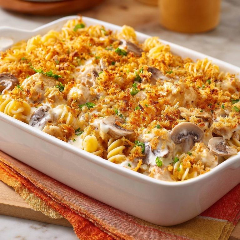 Creamy chicken mushroom rotini bake with a golden crispy topping in a white baking dish.