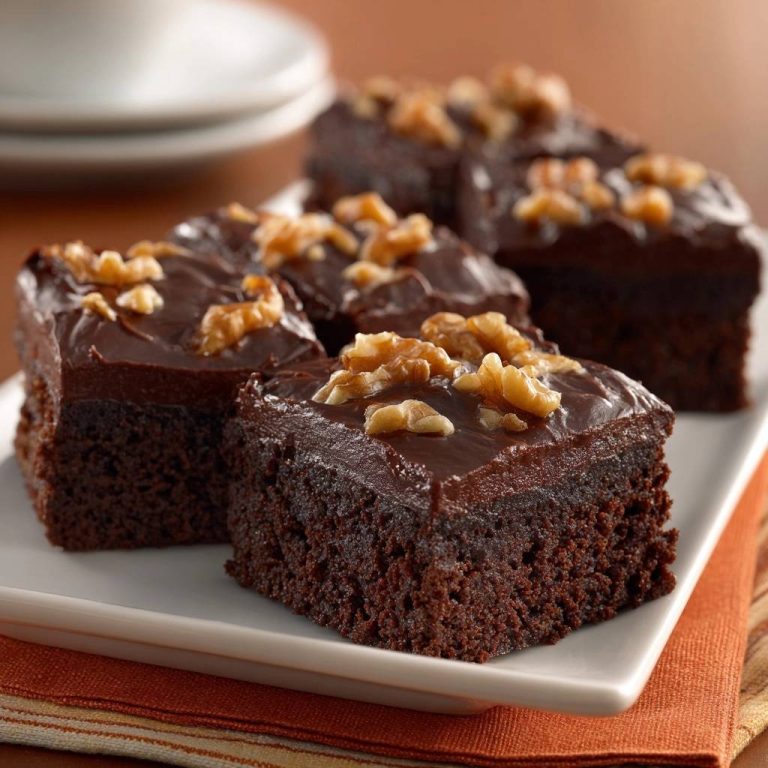 Frosted chocolate walnut cake sliced and presented in a close-up view, showcasing rich frosting and walnuts.