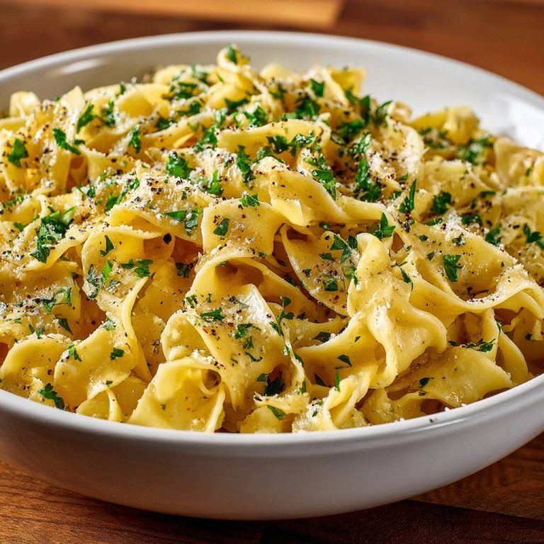 Garlic butter egg noodles with fresh parsley and cracked pepper, presented in a white bowl with a close-up view.