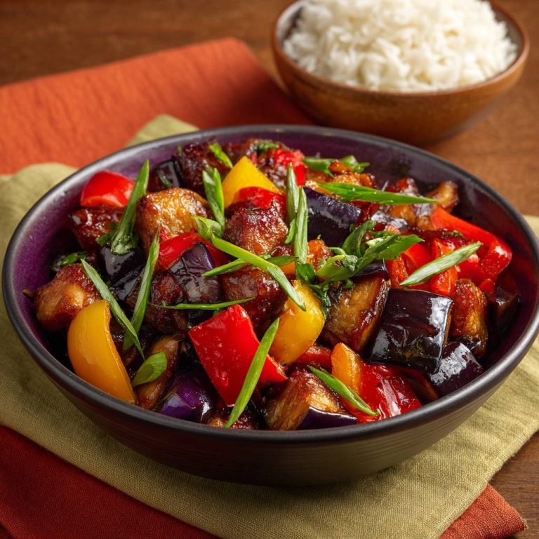 Glazed eggplant pepper stir-fry in a purple bowl with a side of white rice, showcasing glistening vegetables and firm texture.