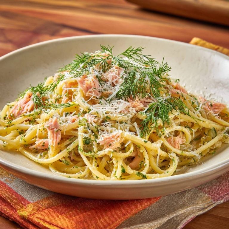 Smoked salmon dill pasta with fresh dill garnish and grated cheese, shown in a close-up view.
