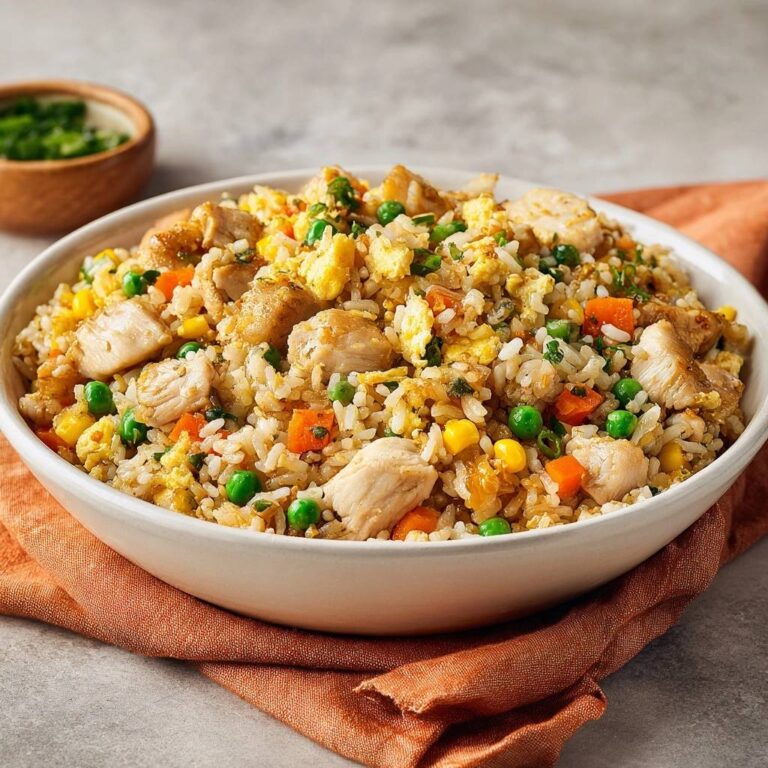 Classic chicken fried rice in a white bowl, featuring tender chicken, fluffy rice, peas, carrots, and scrambled egg.